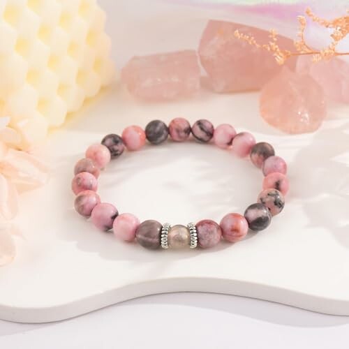 Bracelet en pierres roses sur une surface blanche.