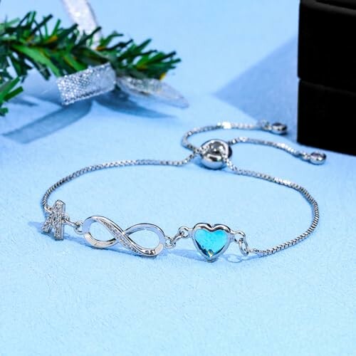 Bracelet en argent avec symbole infini et cœur bleu.